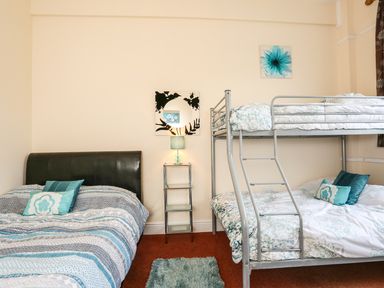 A bedroom with a double bed and a bunk bed with a small table and lamp between them at The Cabin in Combe Martin