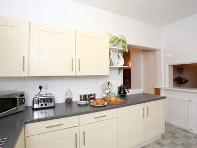 A kitchen with cream cabinets a microwave toaster kettle croissants and orange juice at The Cabin in Combe Martin