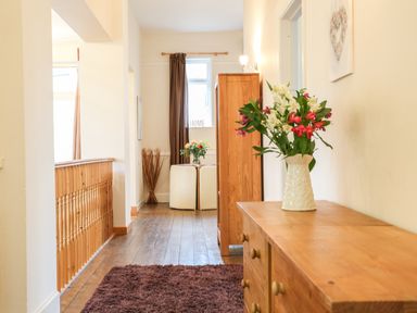 A hallway with wooden furniture and flowers on a dresser at The Cabin in Combe Martin