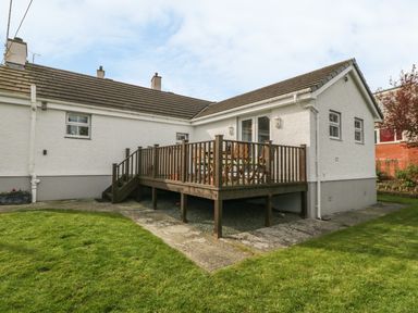 A house with a raised wooden deck and outdoor furniture in a garden at Tyn Y Giat in Brynsiencyn near Beaumaris