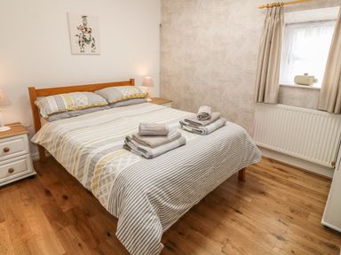 A bedroom with a wooden bed and linens folded on top at Tyn Y Giat in Brynsiencyn near Beaumaris