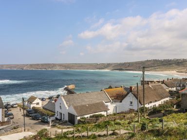 A coastal village overlooking the sea with houses and cars near a beach at Sennen Heights in Sennen Cove near Penzance