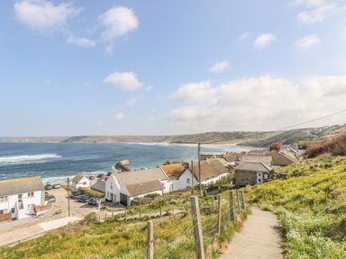 A coastal village with houses along a hillside path and a view of the ocean at Sennen Heights in Sennen Cove near Penzance