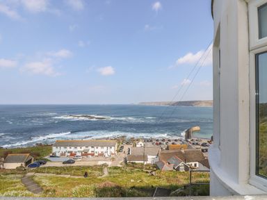 A coastal view with buildings parking lot and ocean waves at Sennen Heights in Sennen Cove near Penzance