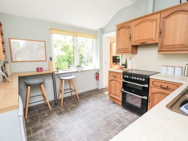 A kitchen with an oven and bar stools at Doe Foot Cottage Ingleton