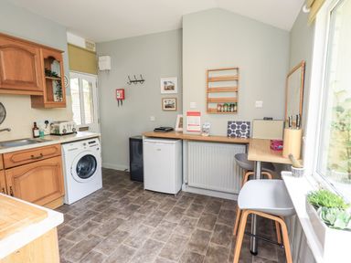 A kitchen with a washing machine and fridge at Doe Foot Cottage in Ingleton