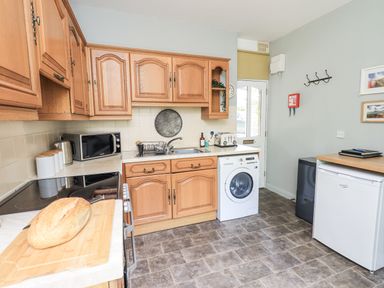 A kitchen with wooden cabinets and appliances at Doe Foot Cottage Ingleton