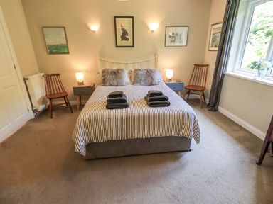 A bedroom with a bed and chairs at Doe Foot Cottage Ingleton