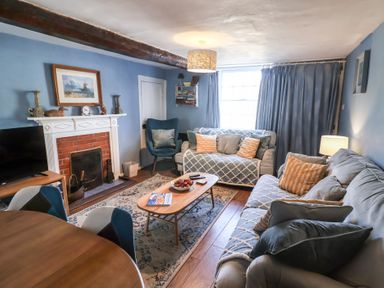 A living room with a sofa and armchair at Delphinium in Blakeney, Norfolk