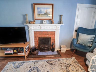 A living room with a fireplace and a television at Delphinium in Blakeney, Norfolk