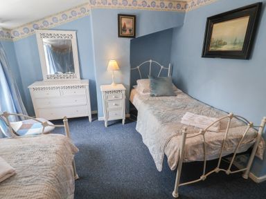 A bedroom with two beds and a dresser at Delphinium in Blakeney, Norfolk