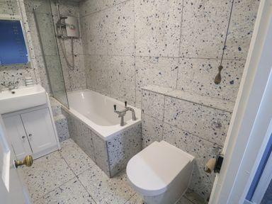 A bathroom with a bathtub, shower, toilet, and sink at Delphinium in Blakeney, Norfolk