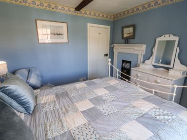 A bedroom with a bed and furniture at Delphinium in Blakeney, Norfolk