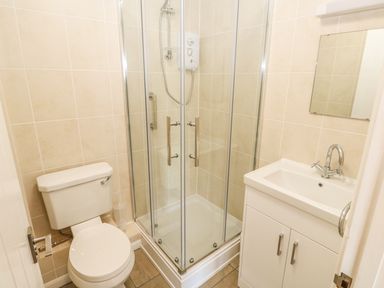 A bathroom with a toilet shower enclosure and sink with cabinet at Surf in Hunstanton