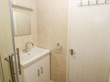 A bathroom with a sink cabinet mirror towel ring and a white door at Surf in Hunstanton