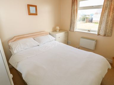 A bedroom with a double bed a white chest of drawers and a window with curtains at Surf in Hunstanton