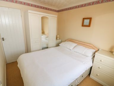 A bedroom with a double bed white wardrobe and chest of drawers at Surf in Hunstanton