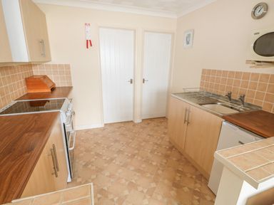 A kitchen with wooden countertops a sink a stove a microwave and two white doors at Surf in Hunstanton