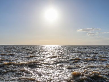 A sun shining over a body of water with small waves at Surf in Hunstanton