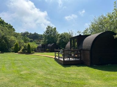 Wooden cabins with decking and outdoor seating at Idris Pod in St Asaph