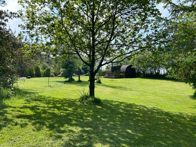 A garden with grass and a wooden structure at Idris Pod in St Asaph
