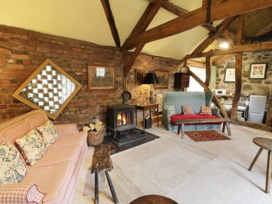 A sitting room with sofas a wood burning stove and exposed wooden beams at Dolgenau Hir - The Barn in Llawr y Glyn near Trefeglwys