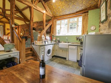 A kitchen with appliances and wooden beams at Dolgenau Hir - The Barn in Llawr y Glyn near Trefeglwys