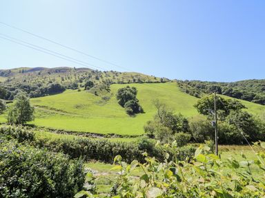 A landscape with green hills trees and power lines at Dolgenau Hir - The Barn in Llawr y Glyn near Trefeglwys