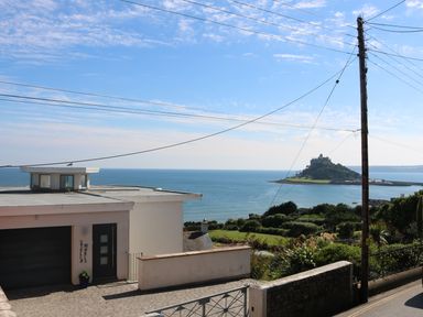 A house near the sea with an island and castle in the background at Ner Sea in Marazion