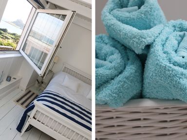 A bedroom with a white bed and a blue and white striped blanket by an open window and a close up of blue rolled towels in a wicker basket at Ner Sea in Marazion