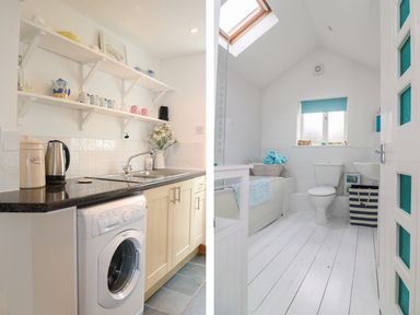 A kitchen area with sink washing machine and shelves next to a bathroom with toilet bathtub and window at Ner Sea in Marazion