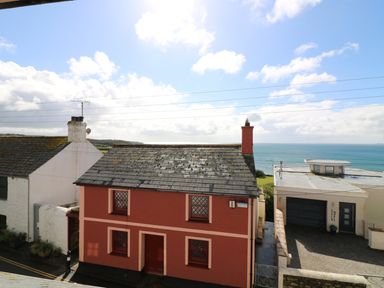 A view of houses with tiled roofs near a coastline with the sea in the background at Ner Sea in Marazion