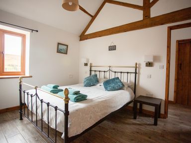 A bedroom with a double bed with folded towels and cushions near a window at 1 Beacon View Barn in Beguildy near Knighton