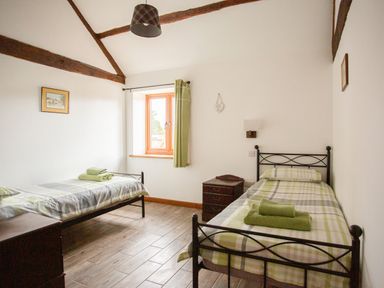 A bedroom with two single beds green plaid bedding and wooden floor at 1 Beacon View Barn Beguildy near Knighton