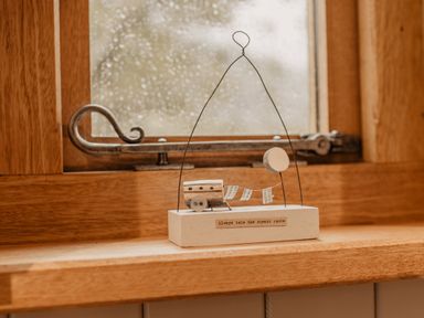 A wooden windowsill with a small decorative piece featuring a caravan and balloon with a quote at Moelfre - Shepherds Hut in Llanbedr