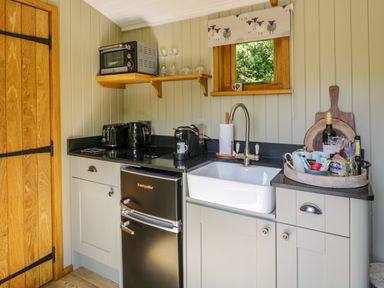 A compact kitchen with a sink and countertop appliances including a toaster and kettle at Moelfre - Shepherds Hut in Llanbedr