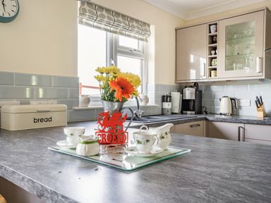 A kitchen with a countertop displaying a flower vase and tea set at Yr Hen Ffald in Pontarddulais