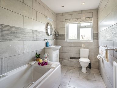 A bathroom with a bathtub sink toilet window and towels at Yr Hen Ffald in Pontarddulais