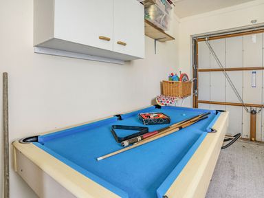 A pool table with cues and balls in a garage with storage cabinets and a wicker basket at Yr Hen Ffald in Pontarddulais