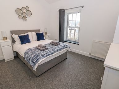A bedroom with a double bed two bedside tables and a window at The Shell at the Hideaway in Tenby
