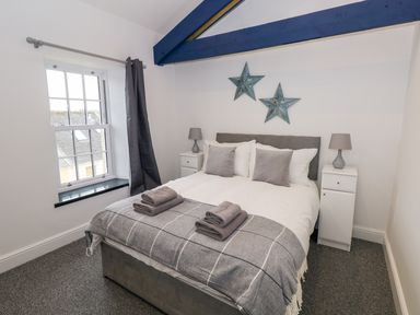 A bedroom with a bed with pillows and folded towels bedside tables with lamps and star wall decorations at The Shell at the Hideaway in Tenby