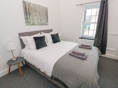 A bedroom with a double bed bedside tables a window and a painting at The Shell at the Hideaway in Tenby
