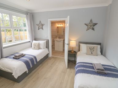 A bedroom with two single beds a window and an open door leading to a bathroom at Castle at The Hideaway in Tenby