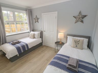 A bedroom with two single beds blue and white throws and a lamp on a side table at Castle at The Hideaway in Tenby
