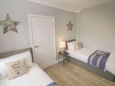 A bedroom with two single beds a small round table with a lamp and star decorations on the walls at Castle at The Hideaway in Tenby