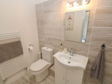 A bathroom with a toilet sink mirror and towel at Castle at The Hideaway in Tenby