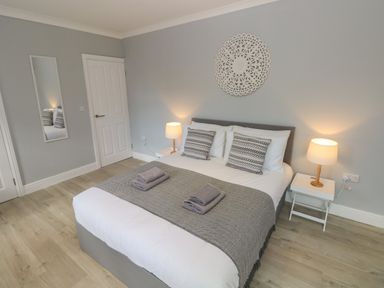 A bedroom with a double bed two bedside tables with lamps a wall mirror and decorative wall piece at Castle at The Hideaway in Tenby