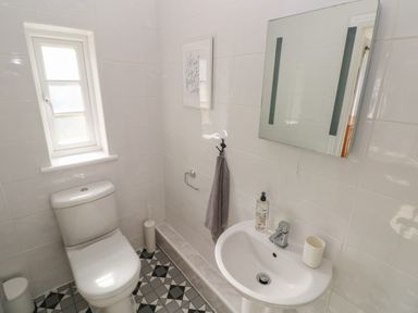 A bathroom with a toilet a sink a mirror and a window at Castle at The Hideaway in Tenby