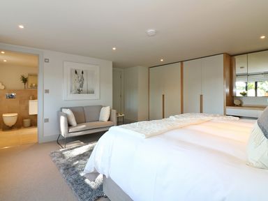 A bedroom with a bed sofa wardrobe and an ensuite bathroom at Mill House Boskensoe Barns in Mawnan Smith near Falmouth