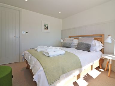 A bedroom with a double bed pillows folded towels bedside tables and lamps at Mill House Boskensoe Barns Mawnan Smith near Falmouth